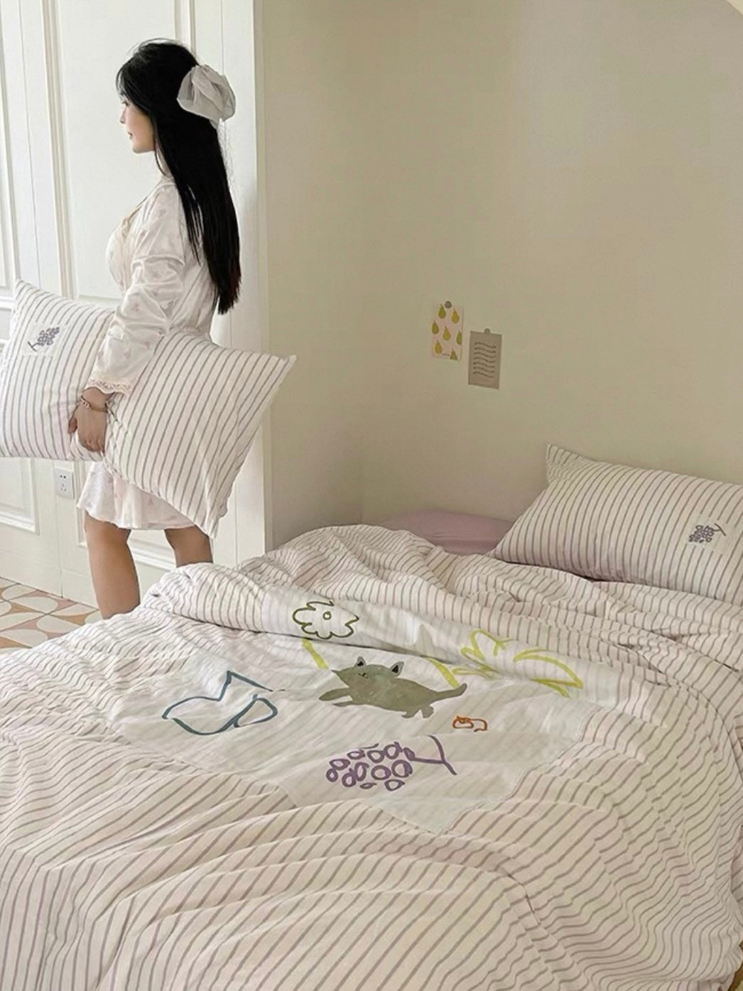 Purple applique bedding spread across a bed while a woman stands beside the mattress.
