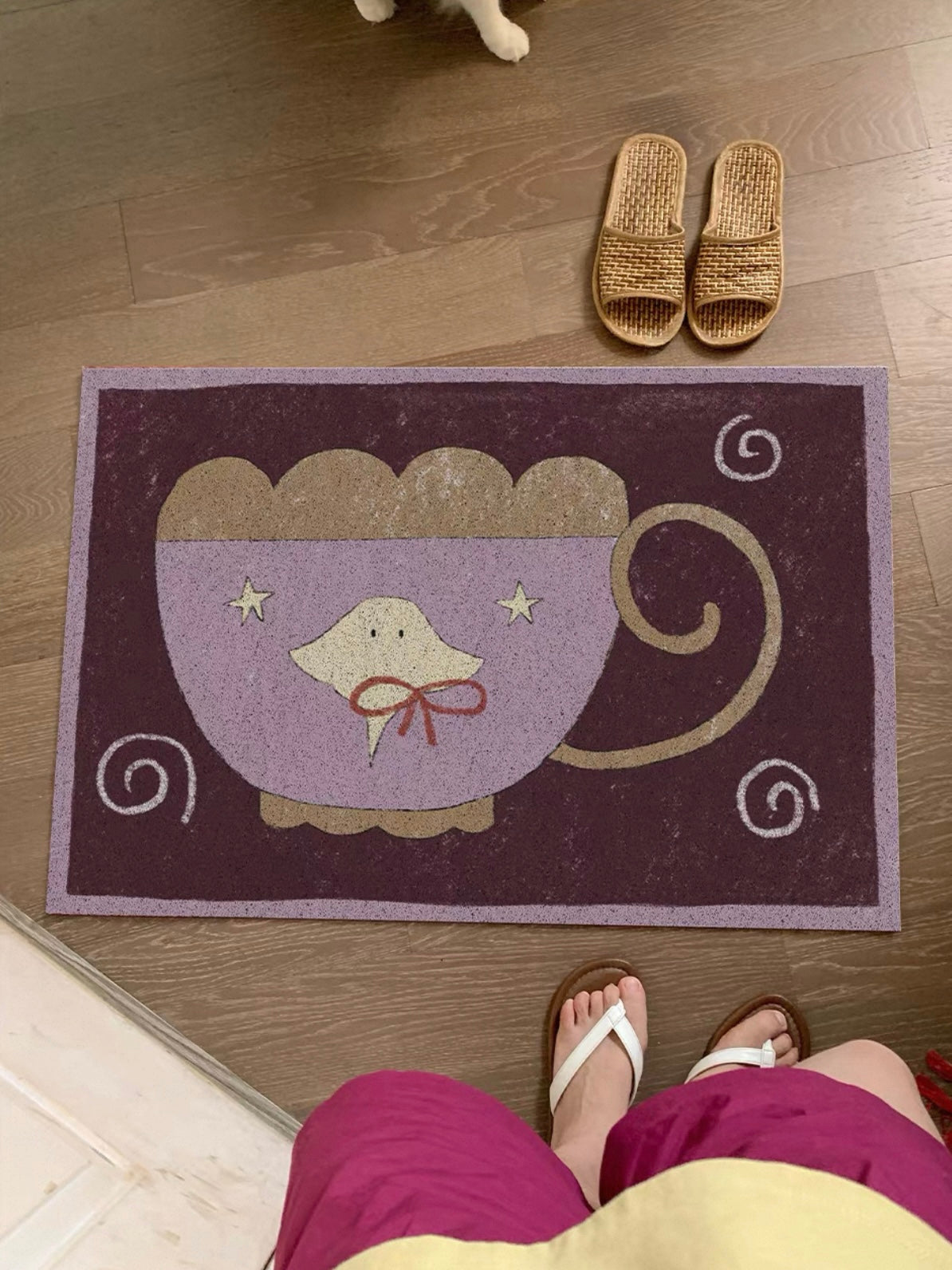 A purple cup rug is viewed from above, with a yellow jellyfish, red bow and pale spirals in view.