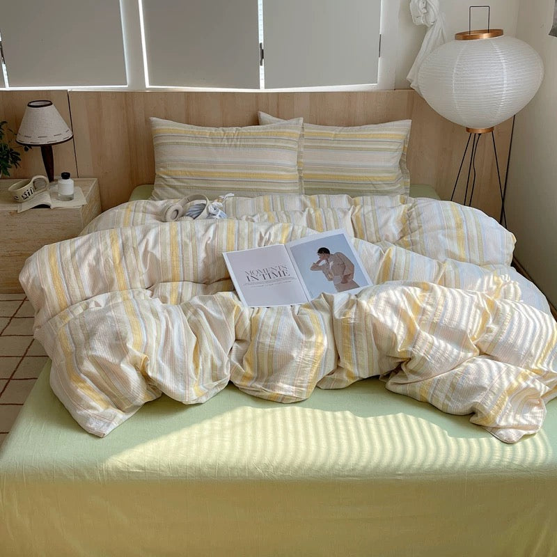 Bed with striped bedding and pillows in a well-lit room.