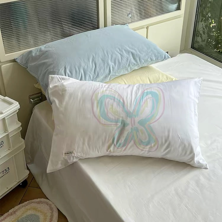 Pastel rainbow butterfly outline centered on the front of a white pillowcase.