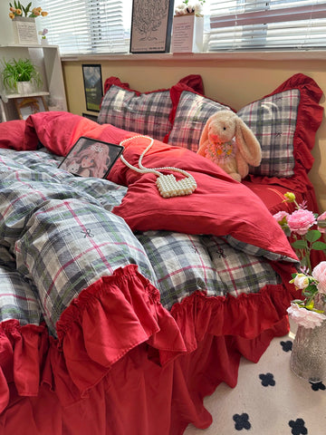 Bed with red and plaid bedding, teddy bear, and pink flowers.