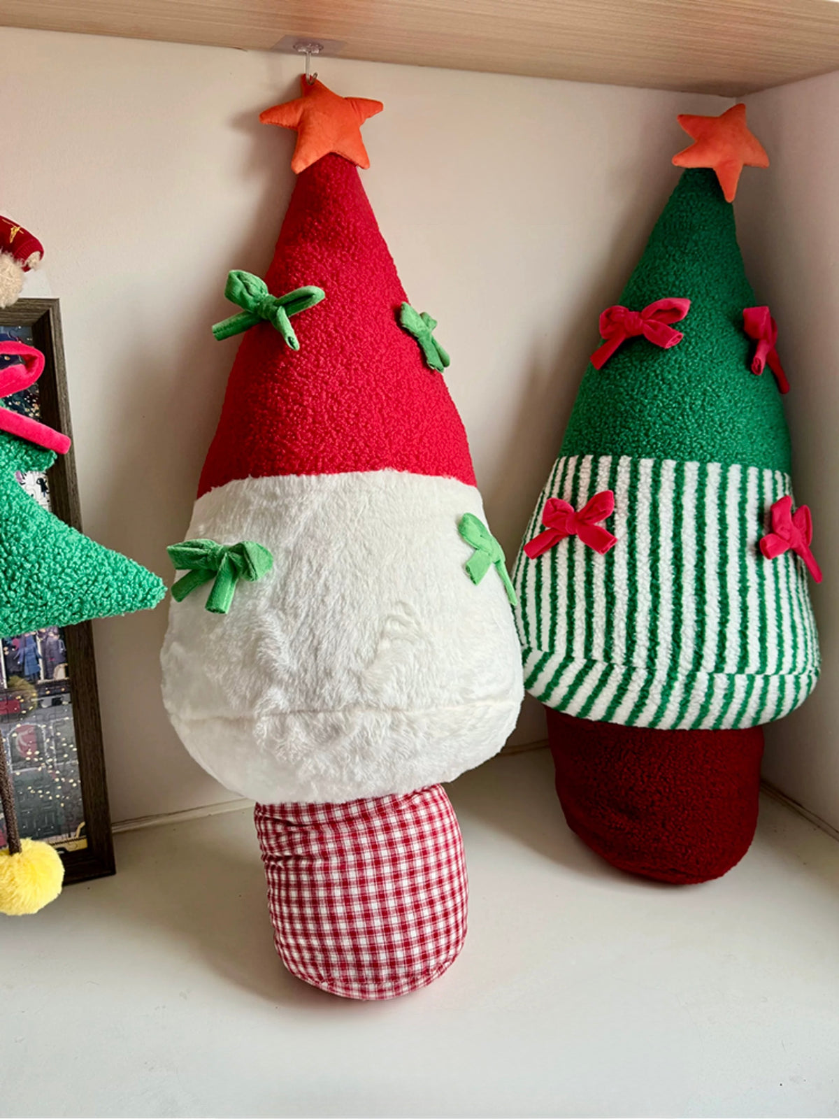 Red and green plush Christmas tree pillows displayed side by side
