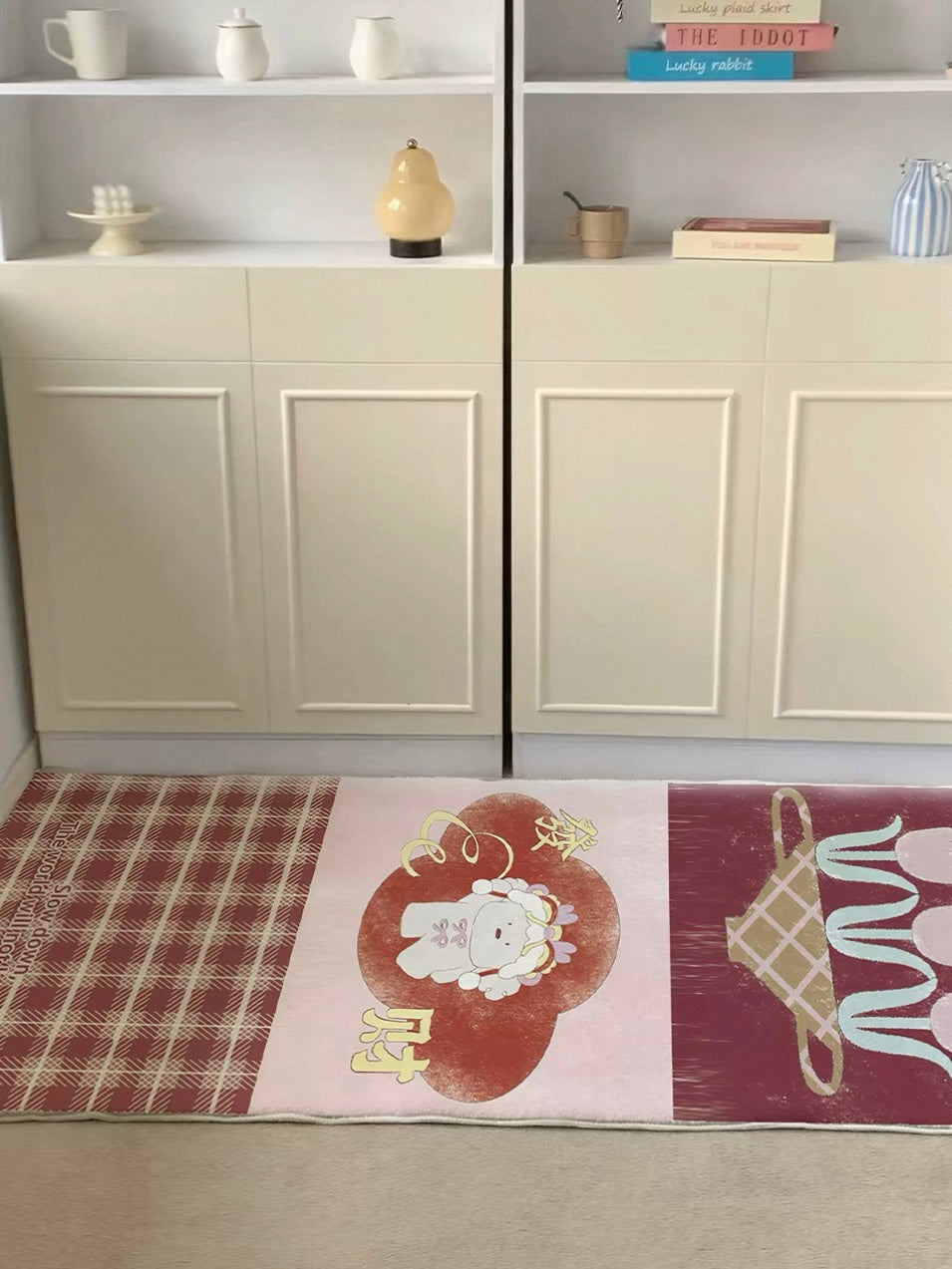A red plaid runner rug is shown horizontally in front of pale cabinets, with the character panel centered.