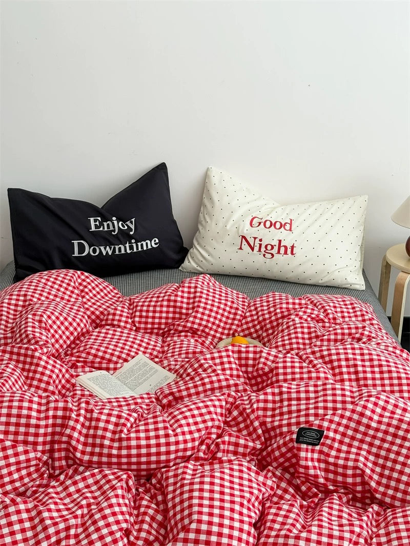 Red and white checkered comforter on a bed with pillows labeled 'Enjoy Downtime' and 'Good Night'.