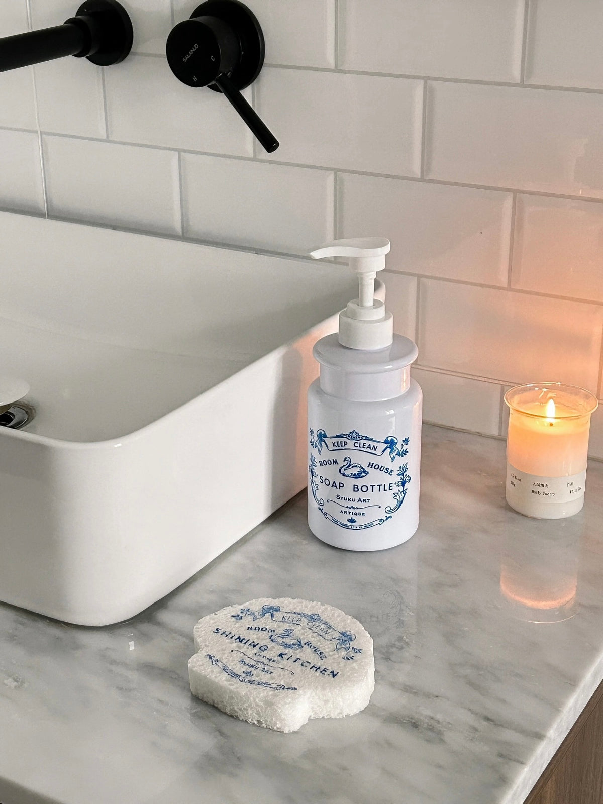 A refillable soap dispenser stands beside a sink, with a matching scalloped sponge resting below the pump.