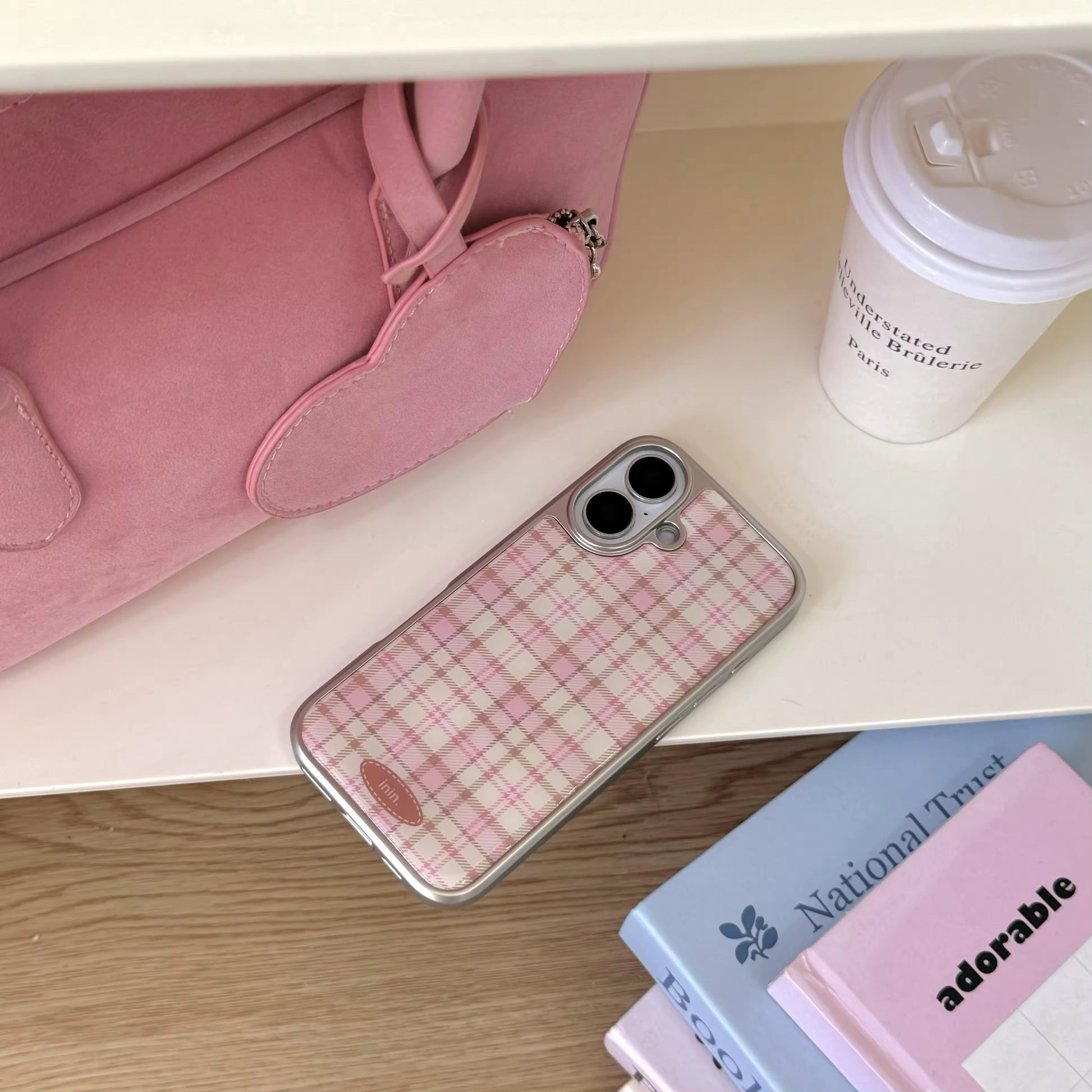 Pink aesthetic phone case lying next to pastel books and a latte cup for cozy desk setup
