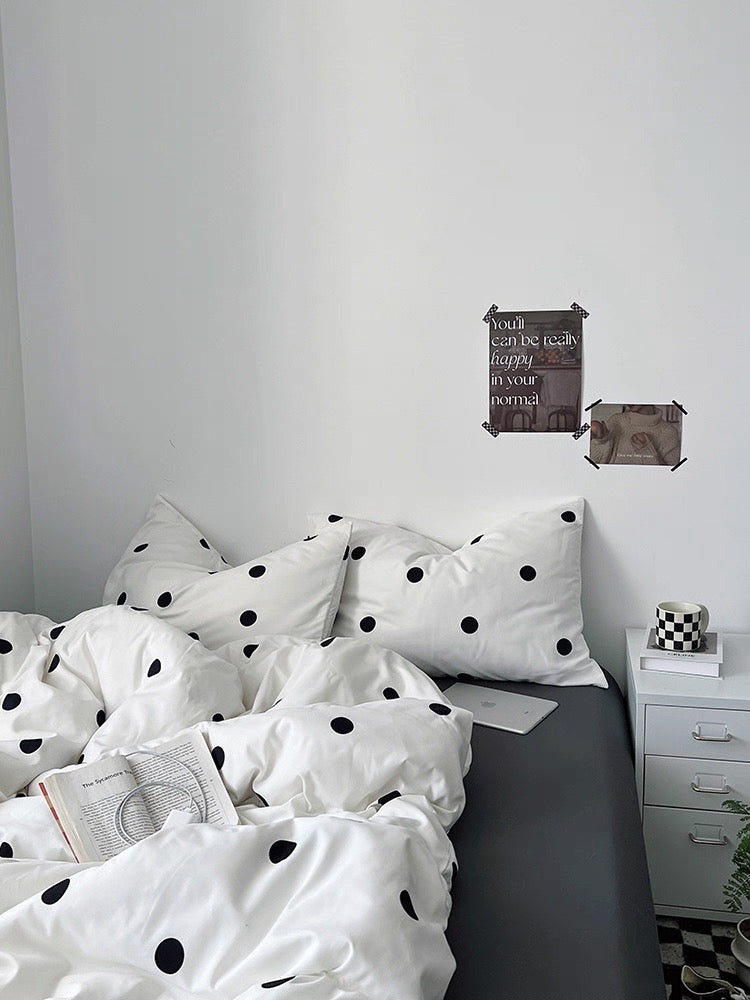 Bed with polka dot bedding in a minimalistic room.