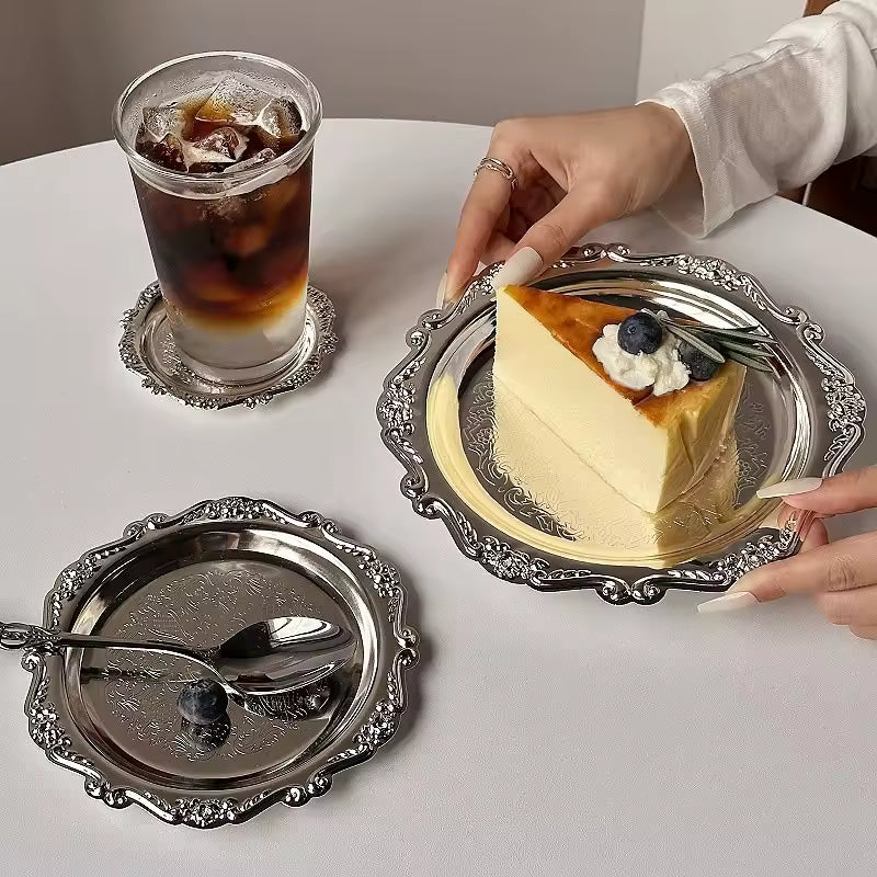 Slice of cheesecake with a glass of iced coffee on a decorative silver tray.