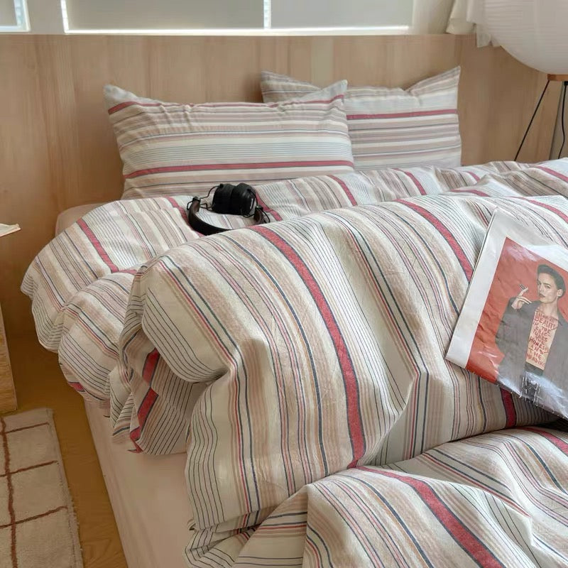 Striped bedspread on a bed with pillows and a magazine in a bedroom setting.