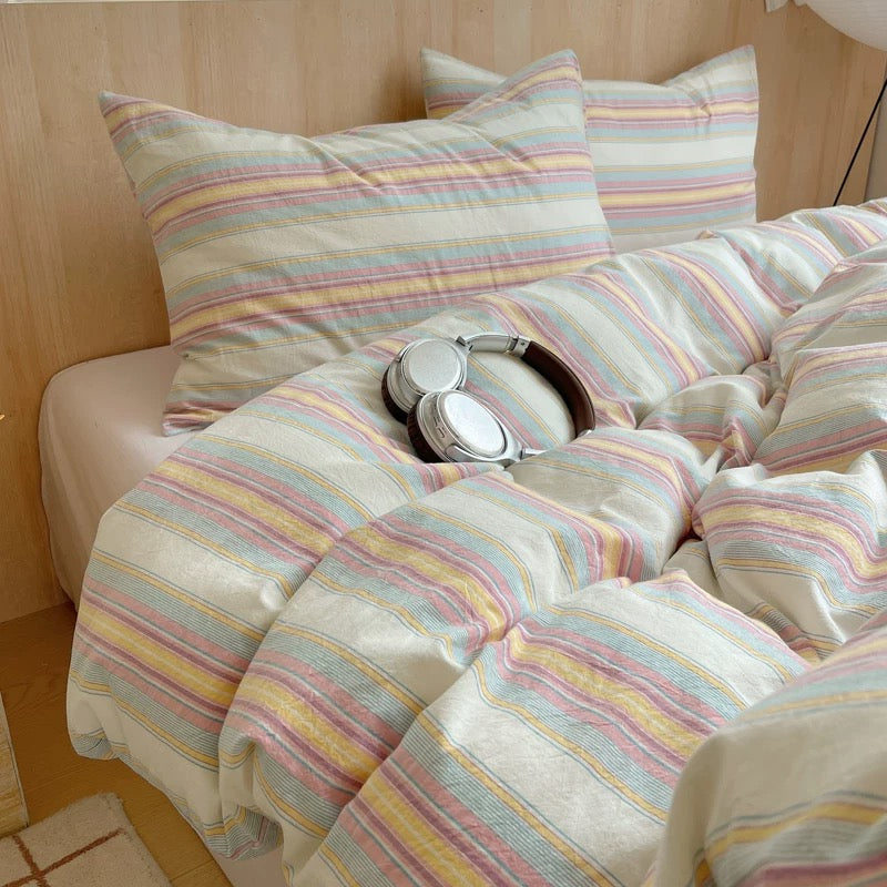 Striped bedding with a pair of headphones on a bed in a bedroom setting.