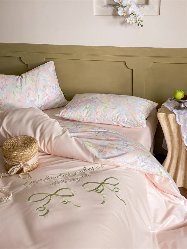Pastel-colored bedding set with floral patterns on a bed in a bedroom.