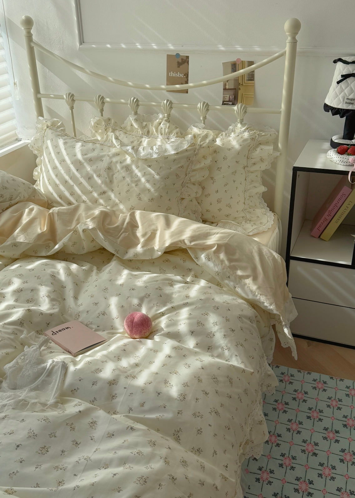 Bed with white bedding and a nightstand with books in a softly lit room.