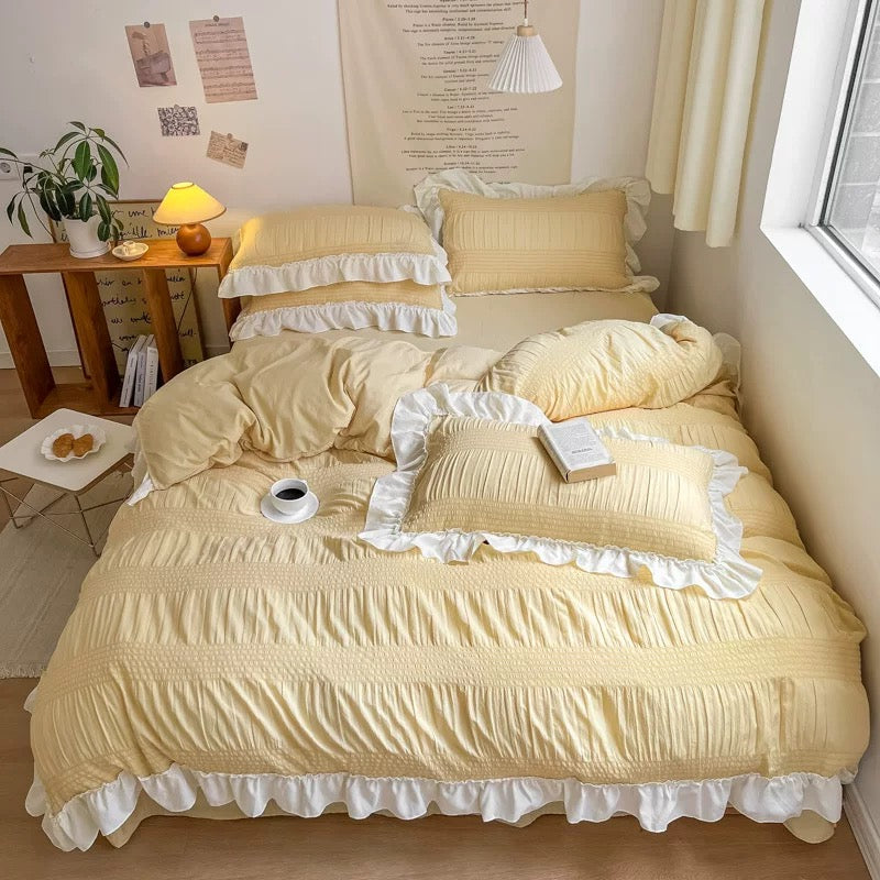 Yellow bedding set with ruffled edges on a bed in a bright bedroom.