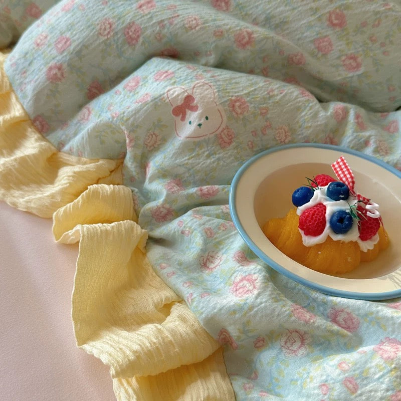 Pastel floral bedding set styled with a plush bunny toy on a crinkled ruffle pillow
