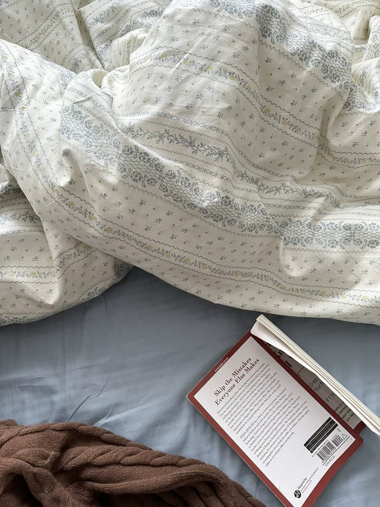 Scandinavian style blue floral duvet cover creating calm reading corner with layered pillows and cotton bedding comfort.