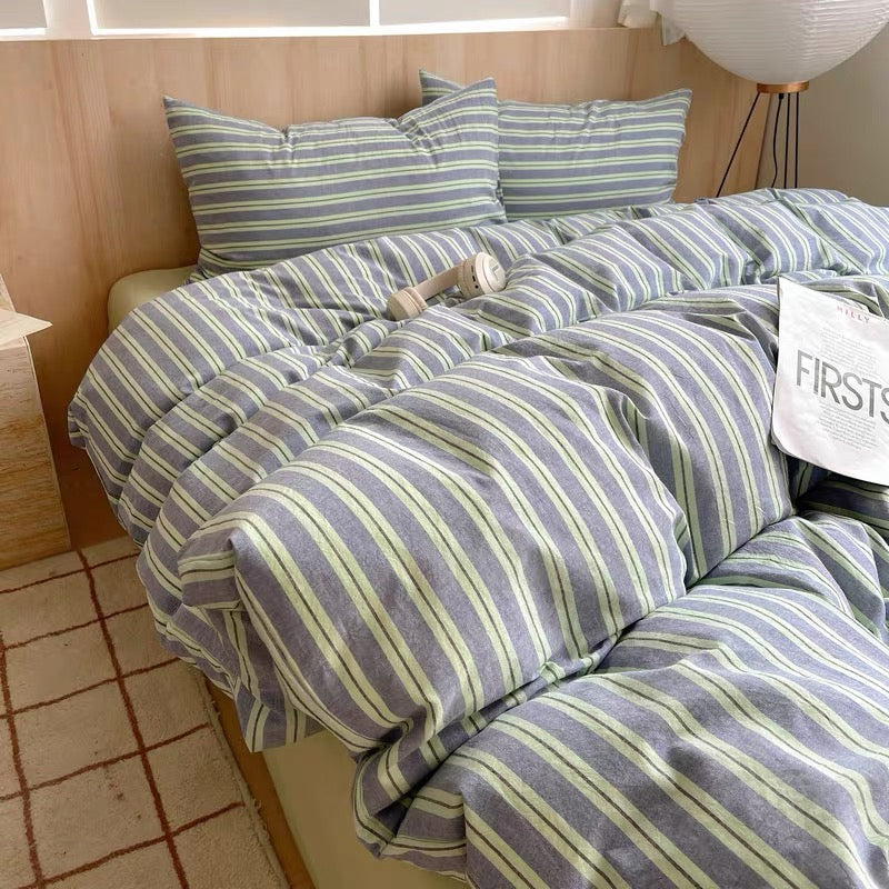 Striped bedding set on a bed with pillows and a visible brand name.