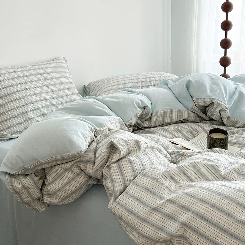 Seafoam blue duvet cover set with matching striped pillowcases arranged against a plain white wall