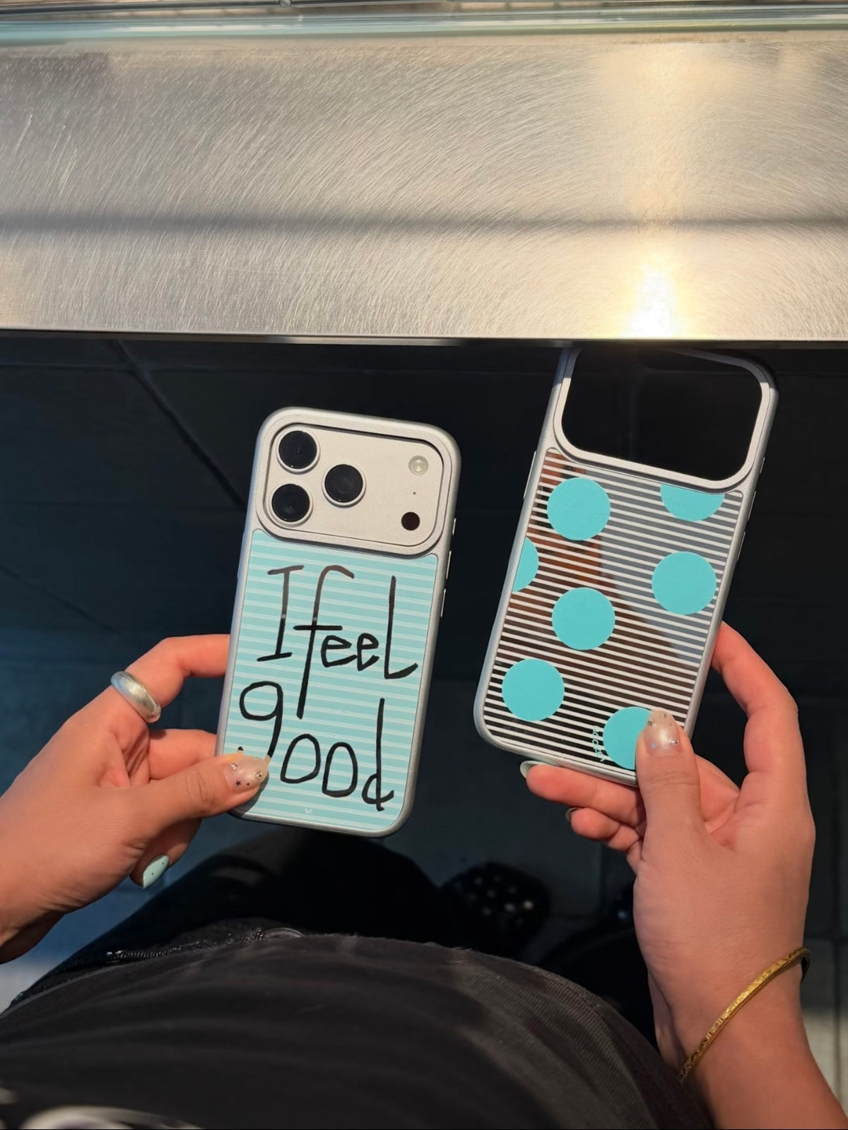 Silver border iPhone cases show aqua stripes and lettering on the left, with aqua dots on the right.