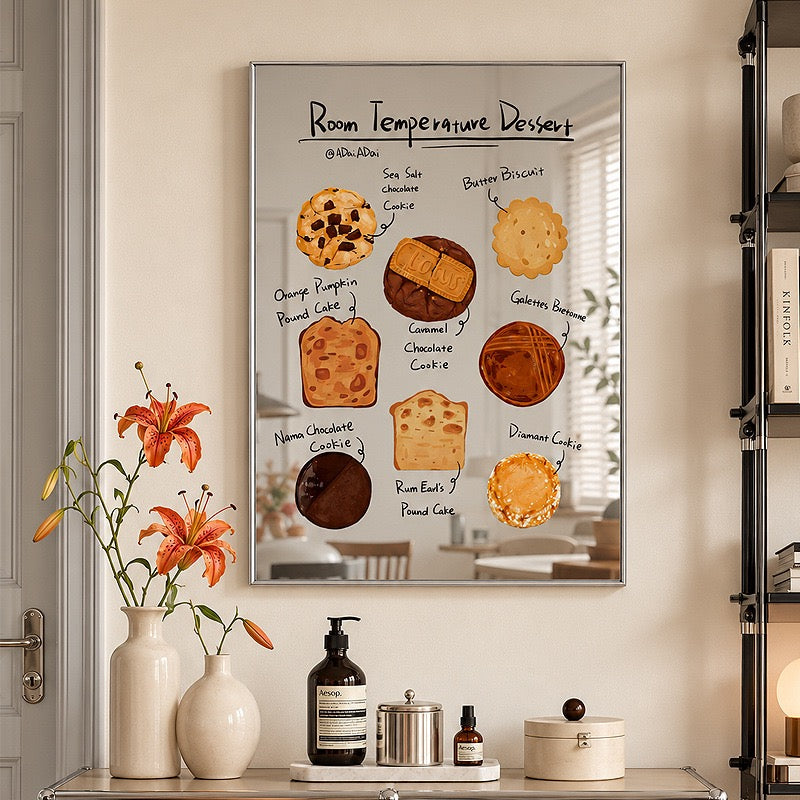 A framed wall art print featuring a dessert-themed recipe poster titled 'Room Temperature Dessert' hangs on a beige wall above a console table with vases, bottles, and containers. The print shows illustrated baked goods and handwritten labels.