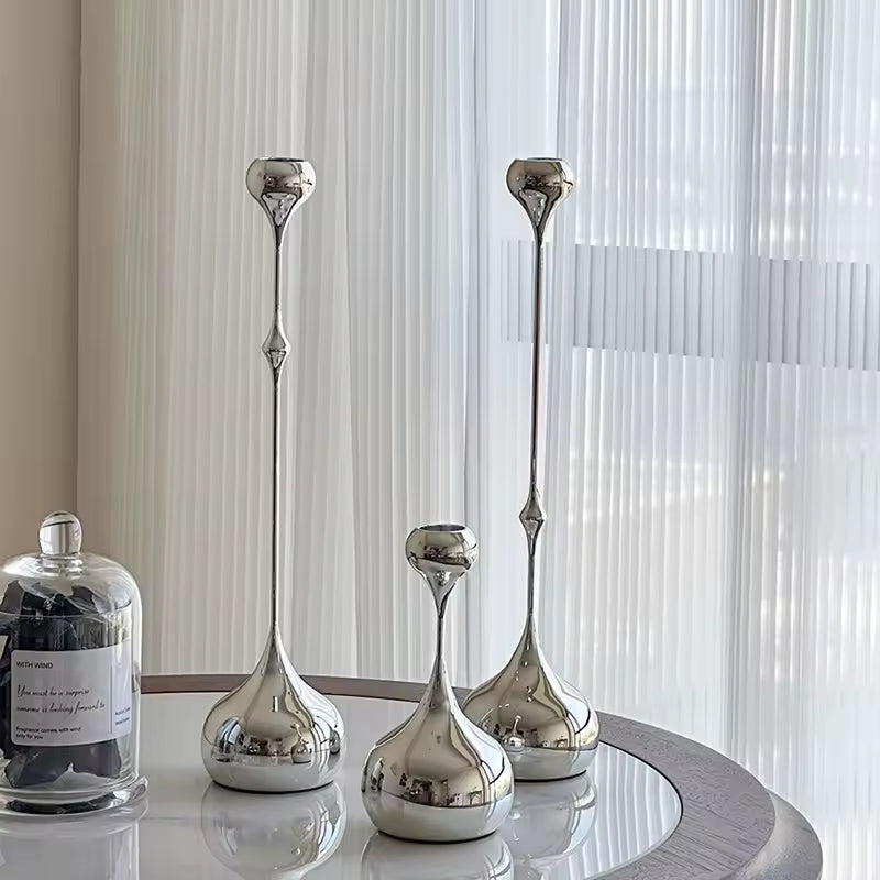 Set of silver decorative vases on a round table with a neutral background