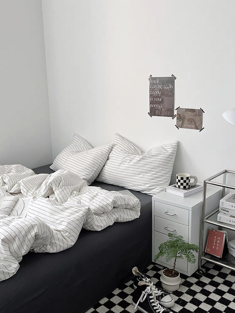 Neatly made bed with striped bedding in a bedroom setting.