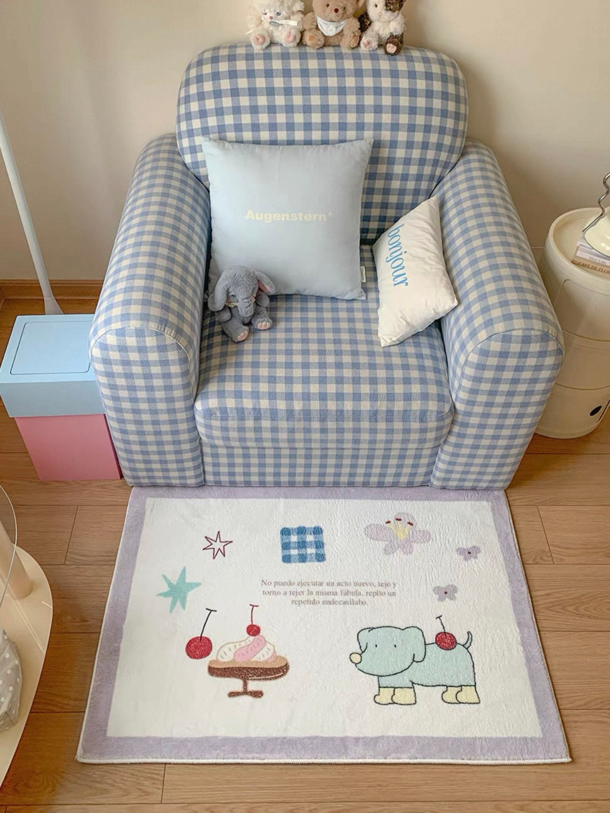 A small accent rug with a purple border sits in front of an armchair, with cherries and a green cartoon animal.