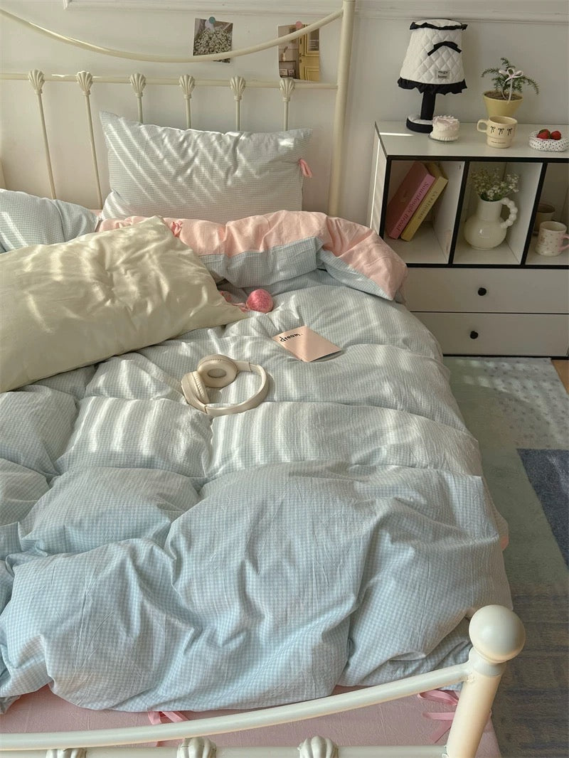 Bedroom with a bed featuring light blue bedding and pink pillows, a nightstand with decorative items.