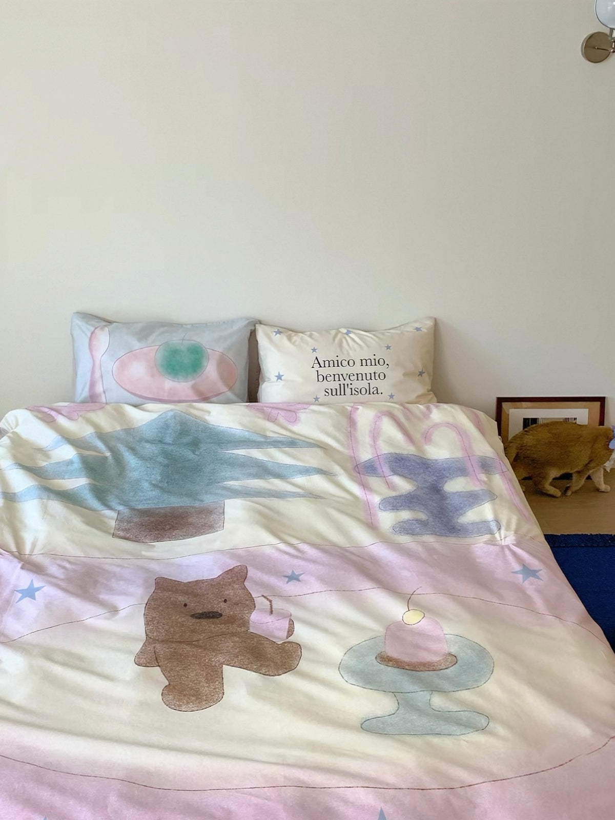 Pastel bear bedding viewed from the side with pale blue and pink areas across the cover.