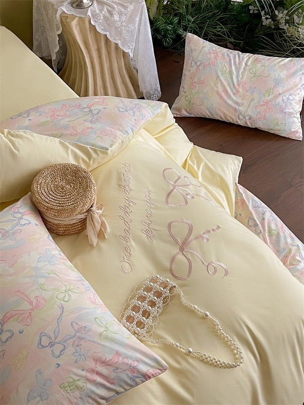 Pastel-colored bedding set with decorative elements on a bed.