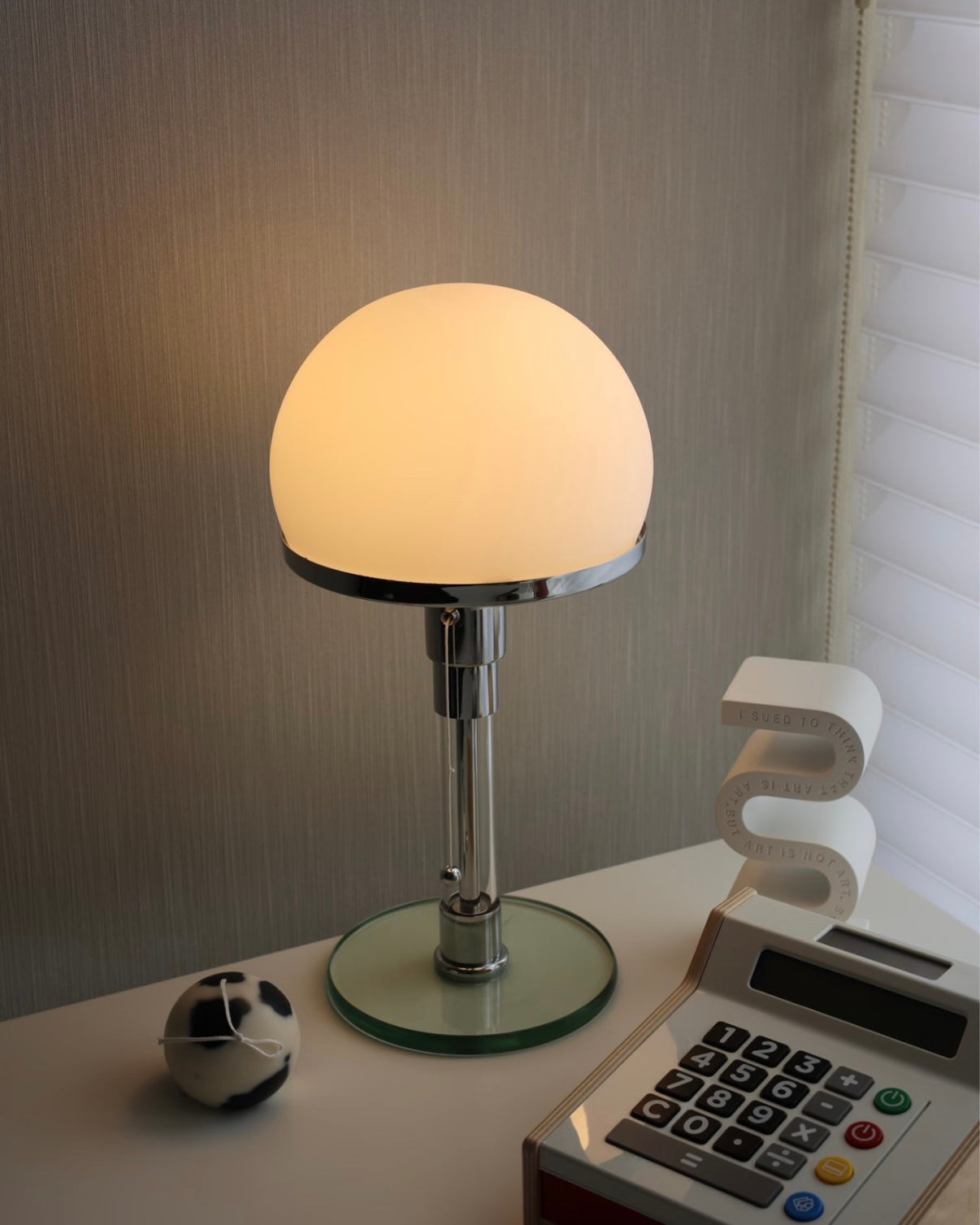 Modern glass table lamp with stainless steel stem and rounded shade for cozy bedside lighting.