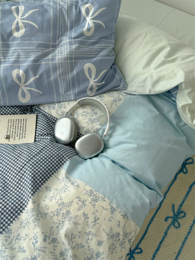 White headphones on a bed with blue and white checkered and floral patterned bedding.