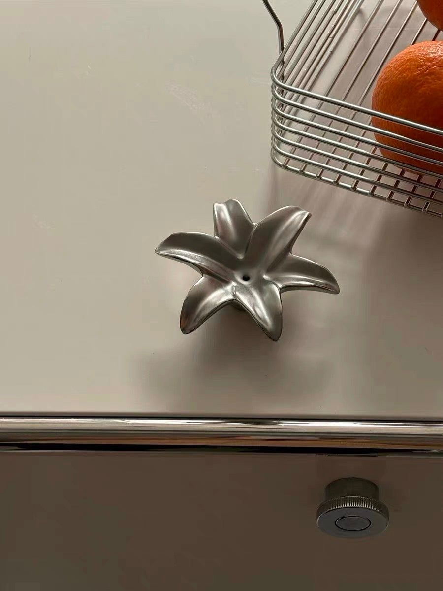 Metallic kitchen tool on a countertop with a basket of oranges in the background