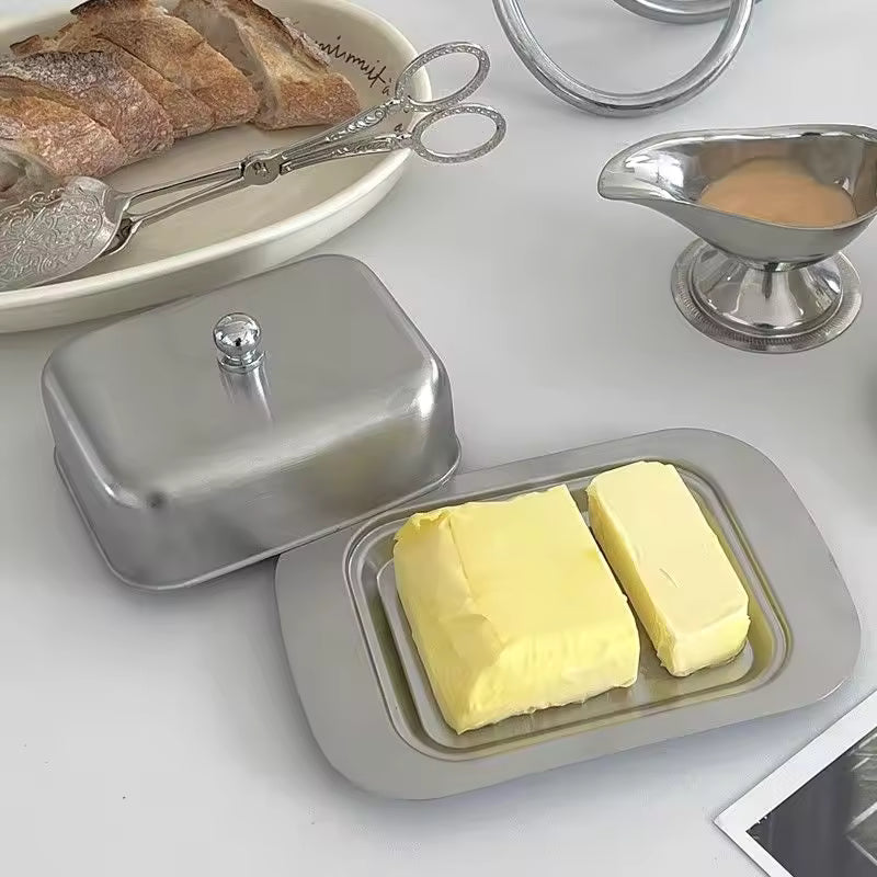 Butter dish with two sticks of butter on a white surface