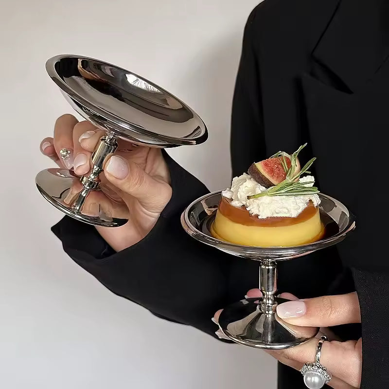 Person holding a silver dish with a dessert on a white background