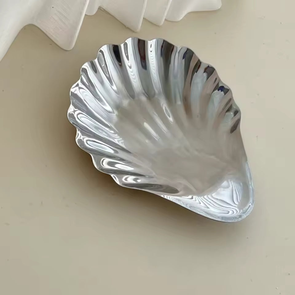 Silver shell-shaped dish on a beige surface
