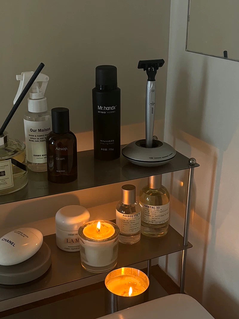 Shelf with various items including a candle, bottles, and a razor.