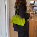Person holding a bright green handbag in an indoor setting.