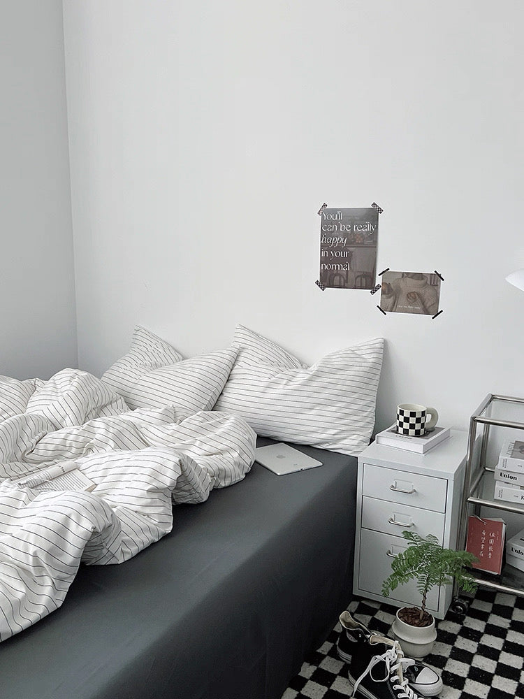 Bedroom with striped bedding, nightstands, and decorative items on a checkered floor.