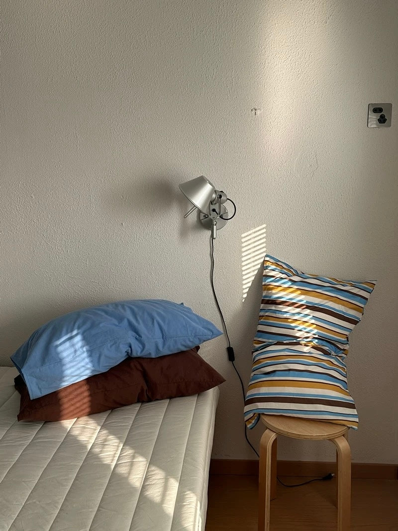 A striped pillow case stands upright beside solid blue and mocha pillowcases.