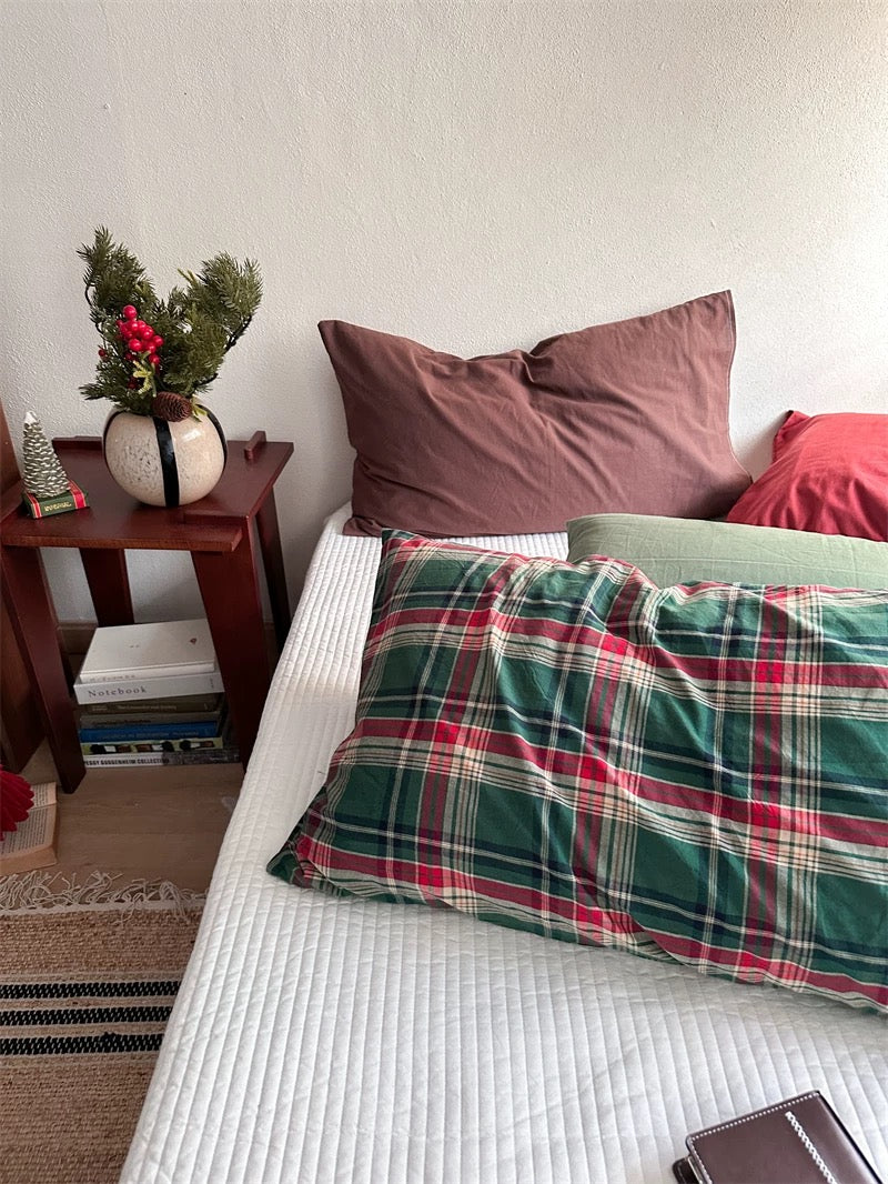 Plaid pillowcases with red bands sit in front of solid chocolate brown and red pillowcases.