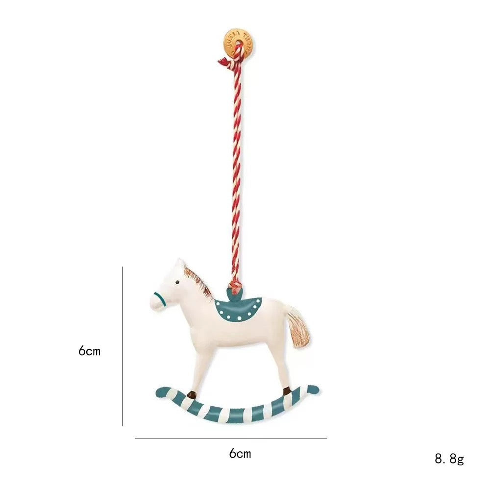 A teal rocking horse Christmas ornament has a white horse, dotted teal saddle and striped curved rocker.