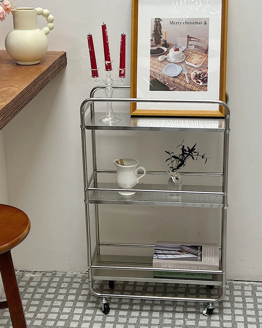 Stainless steel utility cart with wheels styled beside dresser with vases, candles, and diffuser.