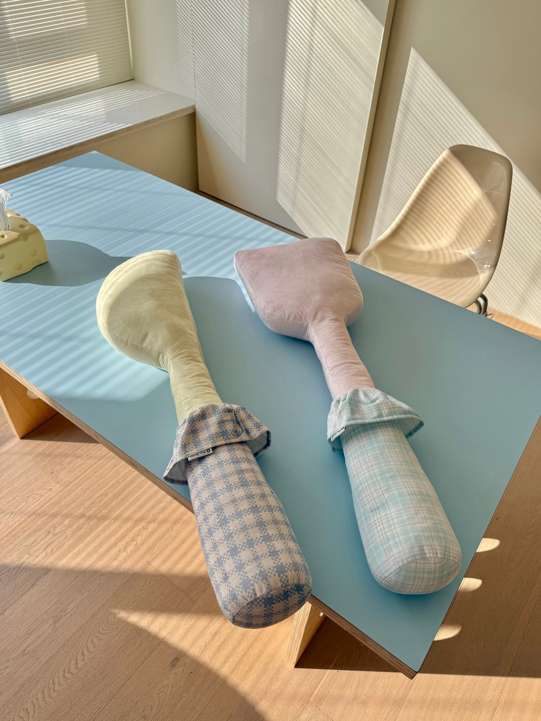 Yellow knife and pink spatula shapes stand upright, with checked handles and fabric collars on each utensil pillow.