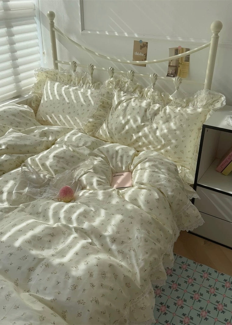 Bed with white floral bedding in a bright room with sunlight filtering through blinds.