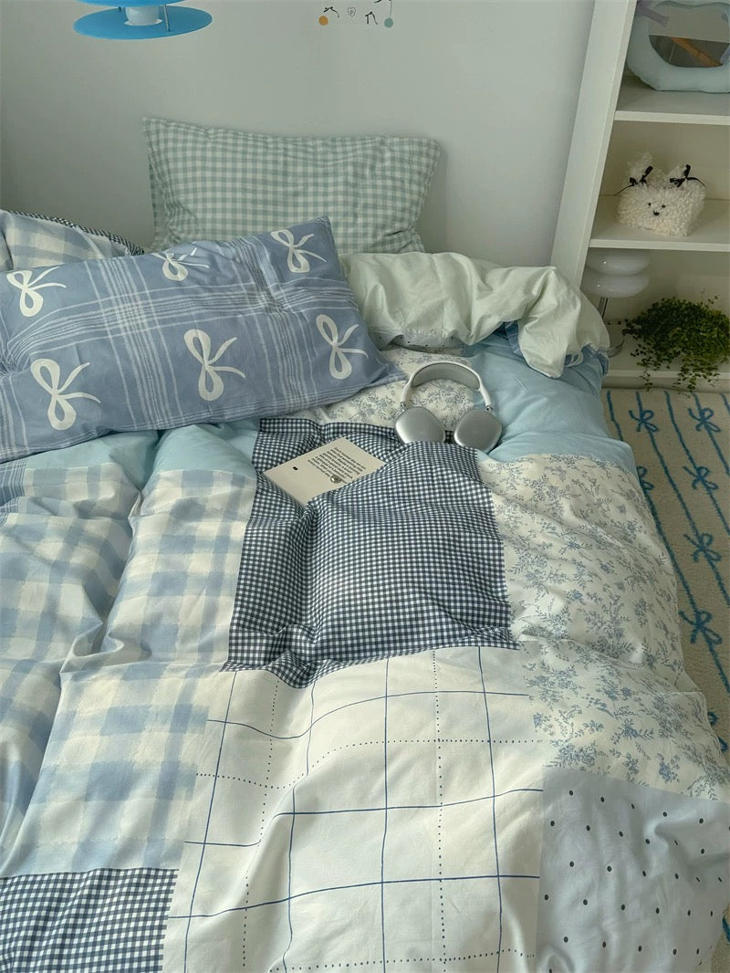 Bed with patchwork quilt and checkered pillows in a room setting.