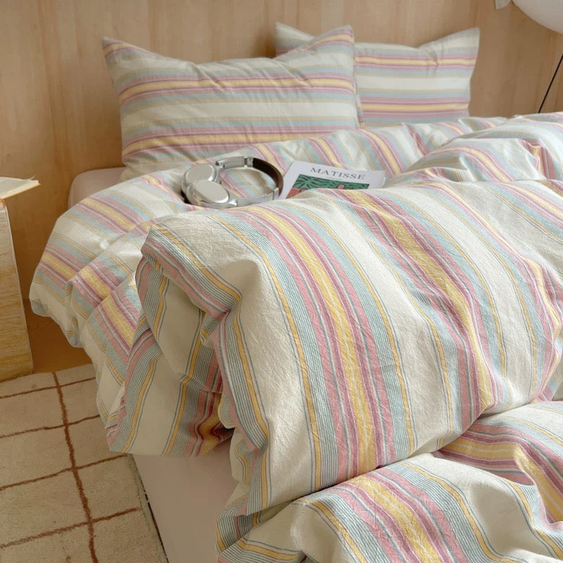 Striped bedding with a pattern of pastel colors on a bed.