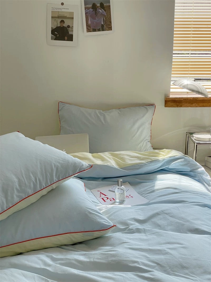 Bed with white pillows and light blue duvet in a bedroom setting.