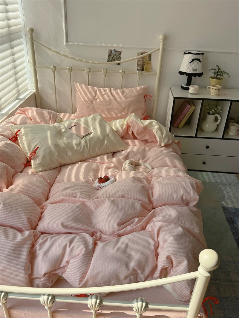 Bedroom with pink bedding and decor, including a nightstand and books.