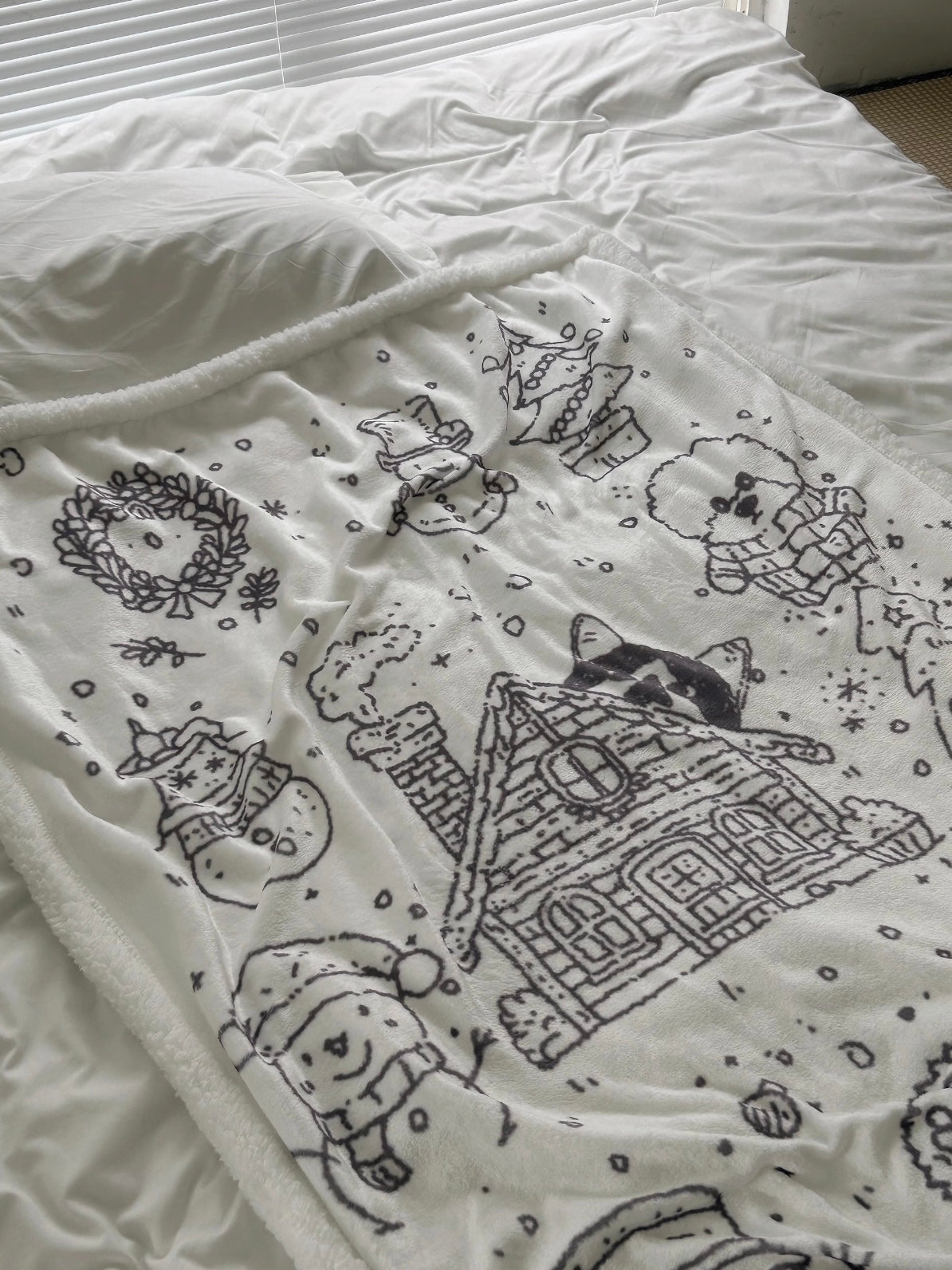 White Christmas fleece blanket folded at the foot of a bed with snowy black line art