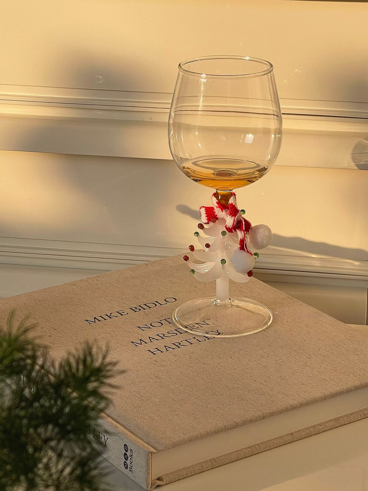 White Christmas tree wine glass with red and green tree detail in warm window light
